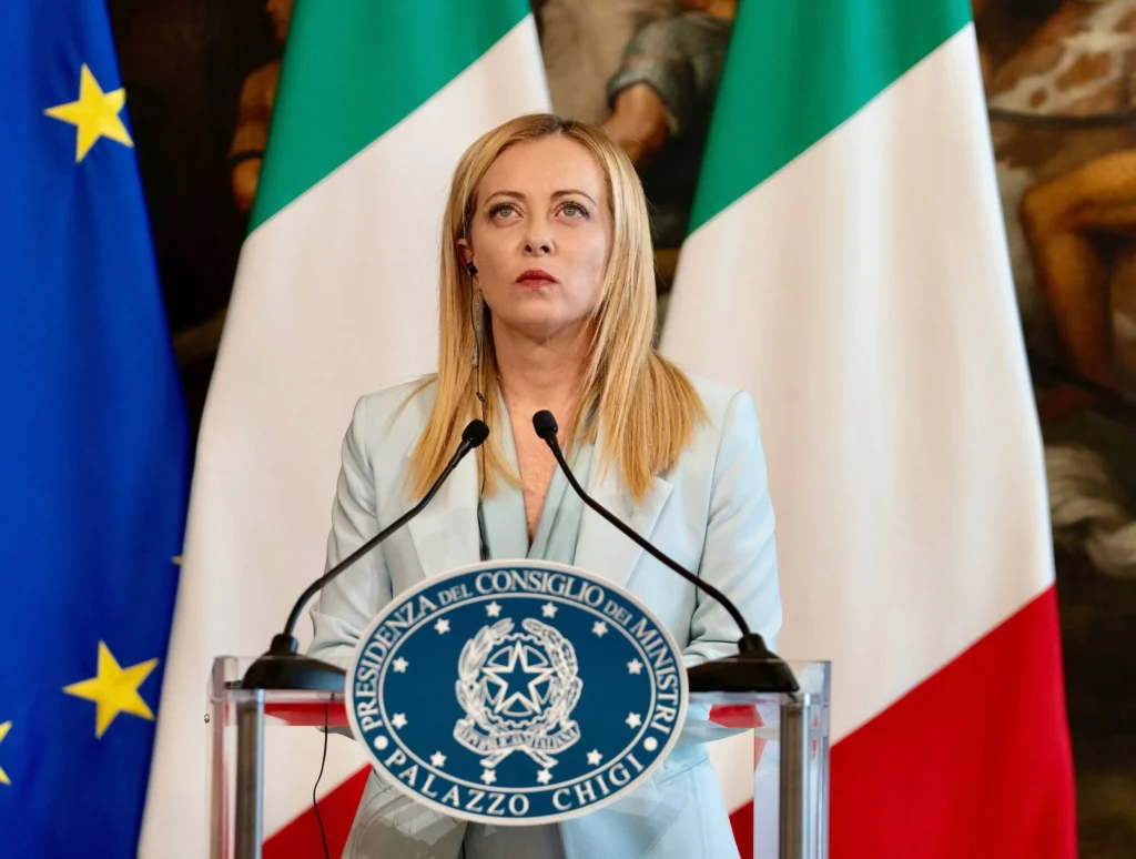 La Première ministre italienne Giorgia Meloni lors d'une conférence de presse avec les drapeaux italien et européen en arrière-plan.